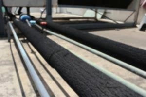 Black foam pipe insulation covering a pipe on a concrete floor. Best pipe insulation for homes and businesses helps prevent frozen pipes and heat loss.