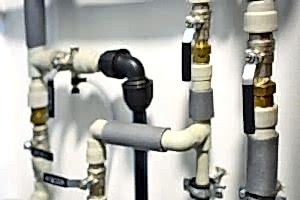 Close-up of pipes and valves connected with metal straps. Strap plumbing is a method that uses metal straps to secure pipes together.