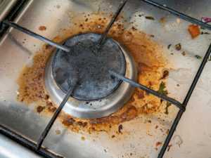 Blocked gas line causing clogged burner ports, leading to reduced performance in gas appliances.