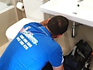 Professional plumber fixing a bathroom sink to identify causes of a persistent smelly drain issue in the home.