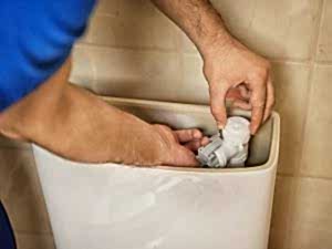 A professional plumber fixing a cistern mechanism inside a tank of a toilet that won't refill.